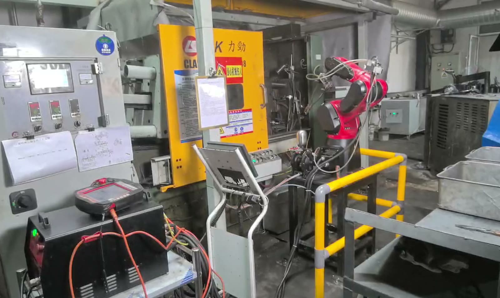 Robotic arm beside die-casting equipment in the factory